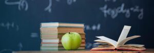 a green apple and books on a table. SAT/ACT® Score Concordance Tables