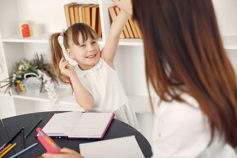 An elementary school student learning english and writing skills from a tutor.