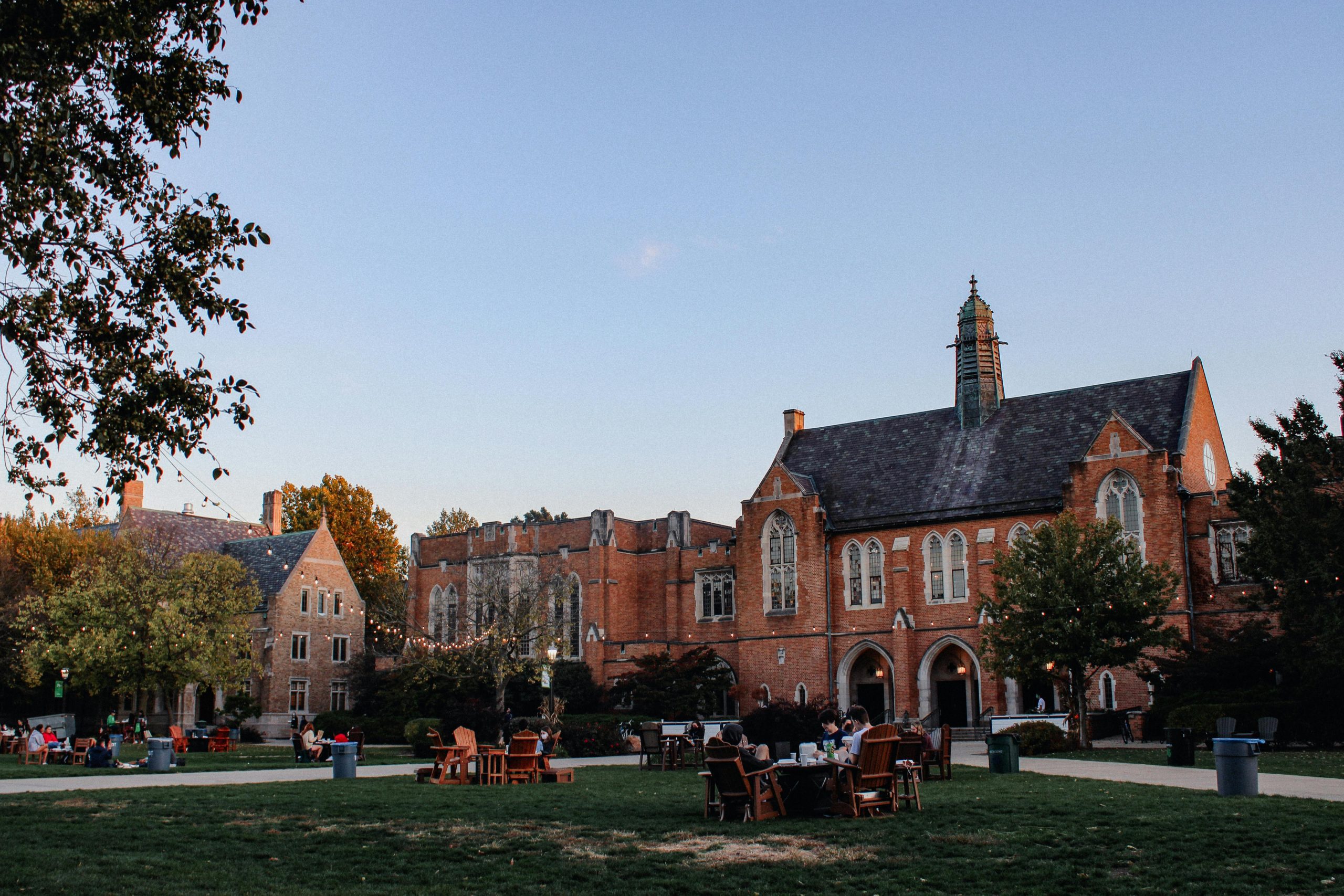 College students sitting on the grass while others tour the campus.